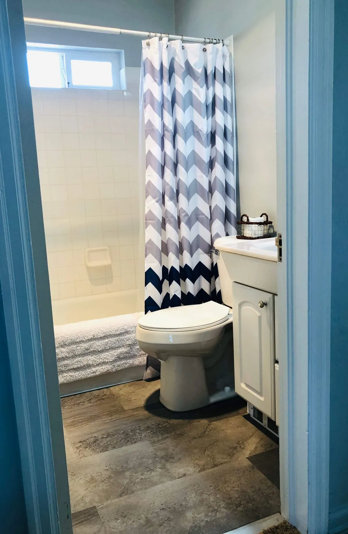 A well-maintained bathroom showcasing a tub/shower combo with a patterned curtain, a clean sink, and a toilet. The scene exudes calm and serenity, ideal for moments of self-care after a day of adventure.