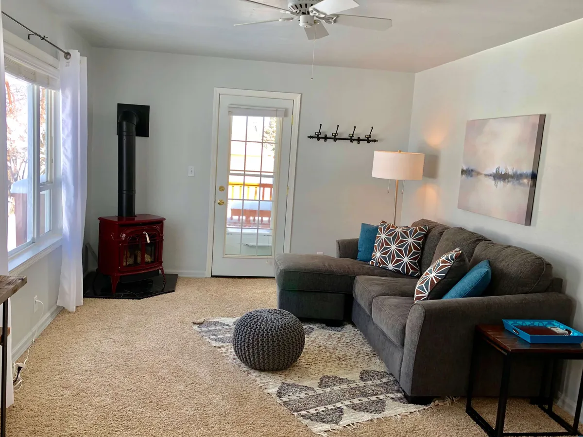 A cozy interior scene with a comfortable sofa, wood stove, and artistic decor, creating a warm and inviting atmosphere. This indoor space offers a glimpse into the relaxation and comfort awaiting inside after time spent outdoors. The ambiance suggests a seamless transition between outdoor adventure and indoor coziness.